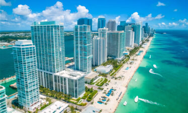 Vue aérienne des gratte-ciel en bord de mer à la Floride en famille sur fond d'océan turquoise et de sable.