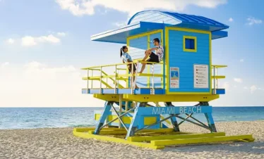 Deux personnes près d'une tour de sauvetage colorée de Miami Beach, profitant de la Floride en famille.