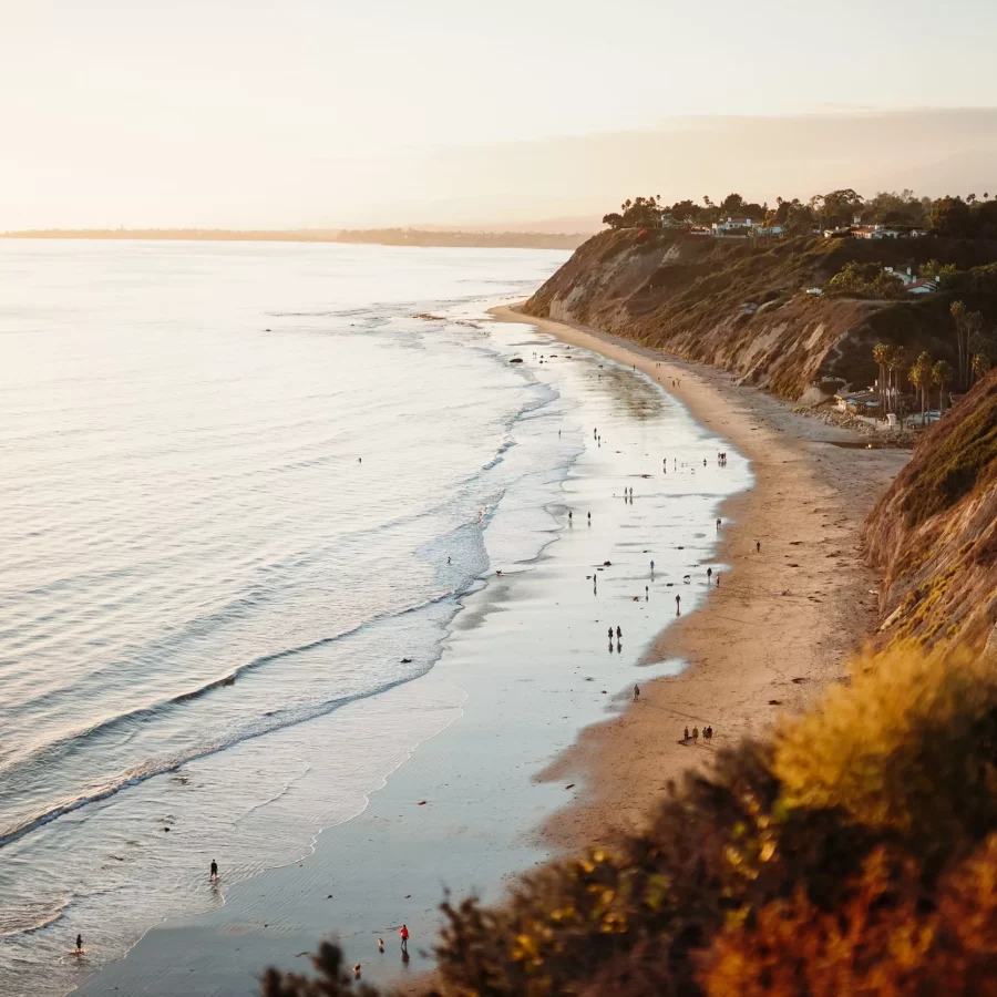 A beautiful shot of people walking in a wild seashore next to low hills