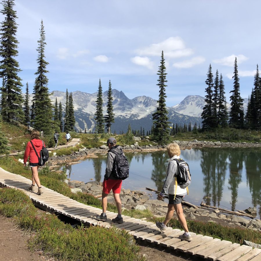 rear-view-people-by-lake-against-sky